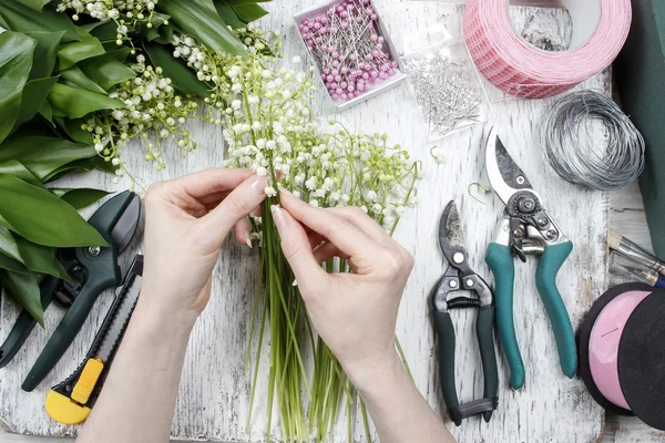 Florista en el trabajo. Mujer haciendo ramo de lirio del valle fluir — Foto de Stock