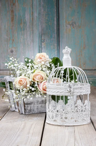 Vintage vogelkooi, mooie roze rozen en Pluimgipskruid — Stockfoto