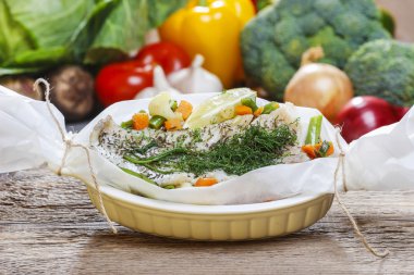 Balık pişirme kağıdı. Arka planda taze sebze