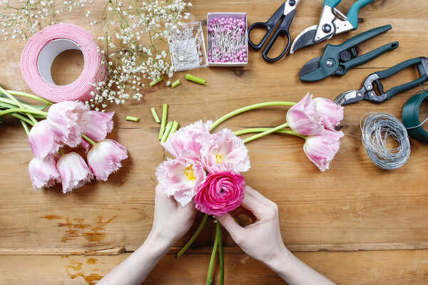 Флорист на работе. Женщина делает красивый букет из розового персидского
 