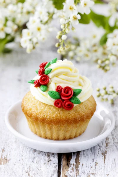 Beautiful rose cupcakes and bird cherries in the background — Stock Photo, Image