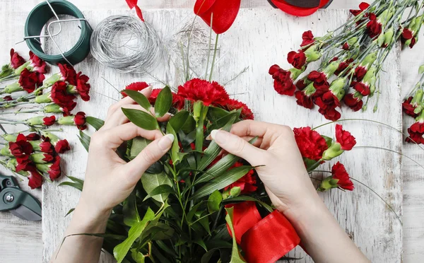Florista no trabalho. Mulher fazendo buquê de flores vermelhas do cravo — Fotografia de Stock