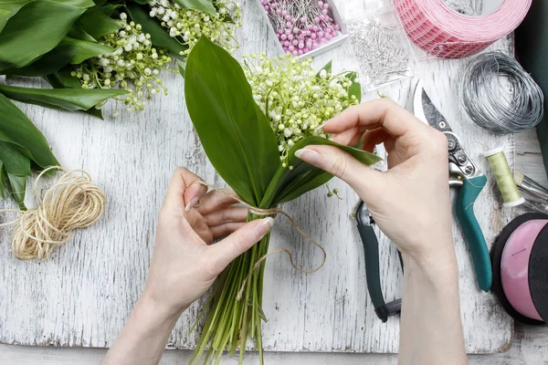 Bloemist op het werk. Vrouw boeket van lily of the valley flow maken — Stockfoto