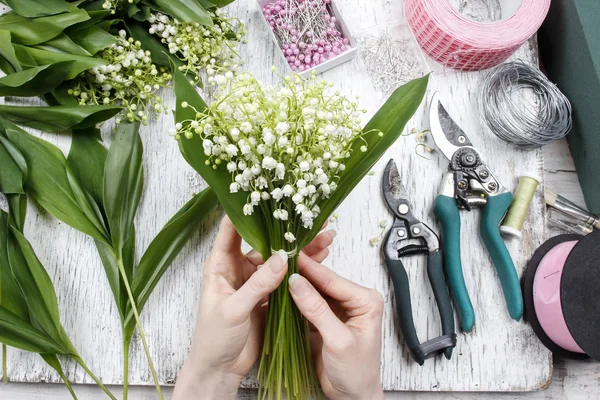 Fleuriste au travail. Femme faisant bouquet de lis de la vallée couler — Photo