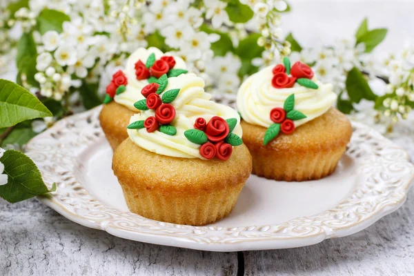 Schöne rosa Cupcakes und Vogelkirschen im Hintergrund — Stockfoto