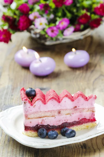 Pembe layer cake ahşap masa üzerine taze meyve ile dekore edilmiştir. sel — Stok fotoğraf