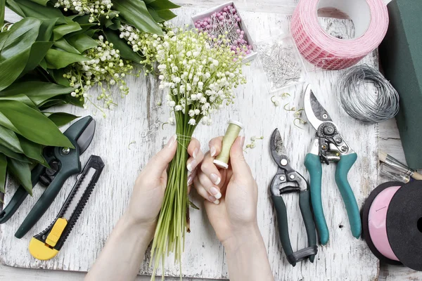 Florist bei der Arbeit. Frau lässt Blumenstrauß aus Maiglöckchen fließen — Stockfoto