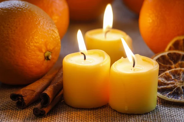 Belle candele e arance succose su tovaglia di iuta — Foto Stock