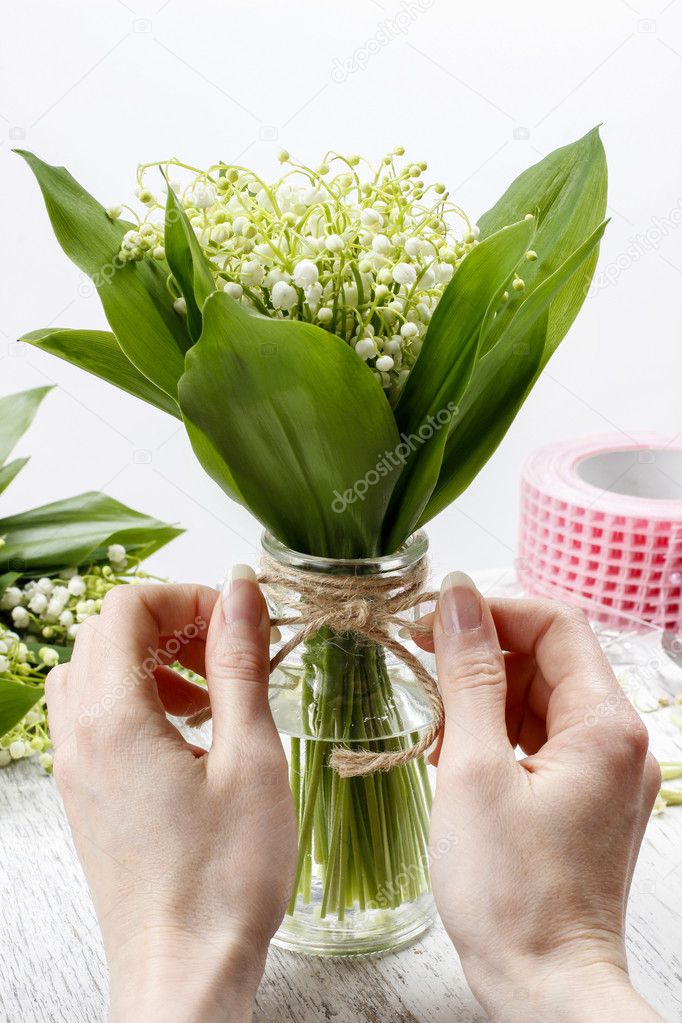 Florist at work. Woman making bouquet of lily of the valley flow
