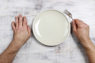 Onun yemek için boş plaka üzerinde ahşap masada bekleyen aç adam