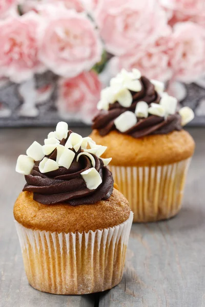 Cupcakes chocolat fantaisie sur table en bois. Fleurs oeillets roses — Photo