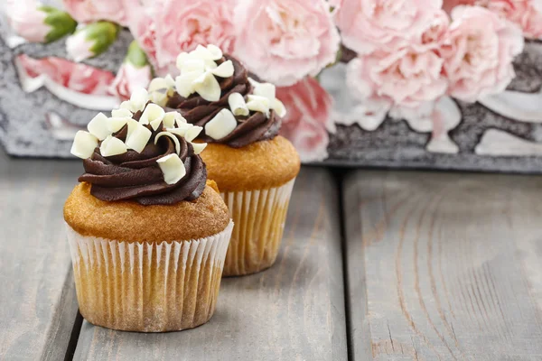 Fancy choklad cupcakes på träbord. Rosa nejlikor blommor — Stockfoto