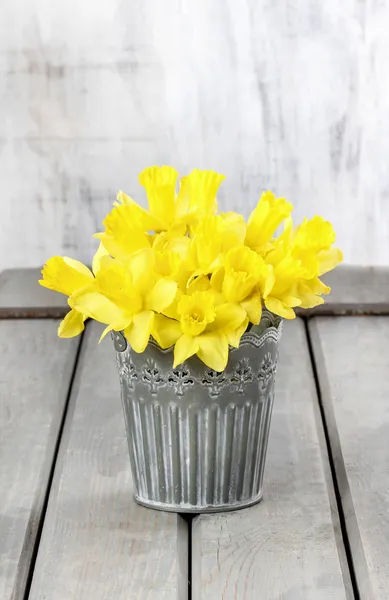 Daffodils in silver bucket on grey wooden table — Stock Photo, Image