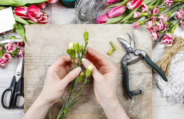 Флорист на работе. Женщина делает весенние цветочные украшения
