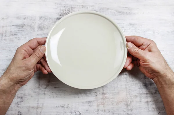 Hombre hambriento esperando su comida sobre un plato vacío en una mesa de madera — Foto de Stock