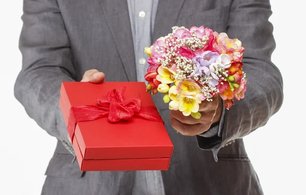 Мужчина держит красочный букет цветов фрезии и красную коробку с — стоковое фото
