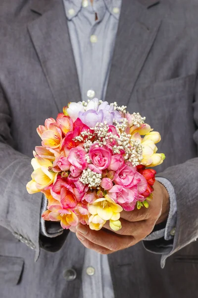 Man holding bouquet of colorful freesia flowers — Stock Photo, Image