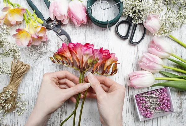 Florist bei der Arbeit. Frau bastelt Strauß aus Frühlingsfreessie-Blumen — Stockfoto