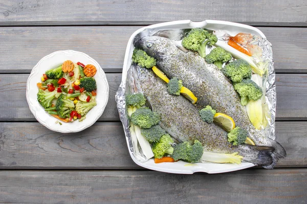 Healthy dinner: trouts and vegetables. Wooden table, top view — Stock Photo, Image