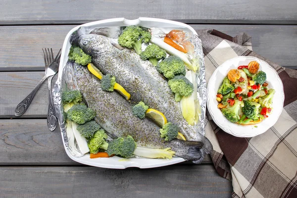 Healthy dinner: trouts and vegetables. Wooden table, top view — Stock Photo, Image