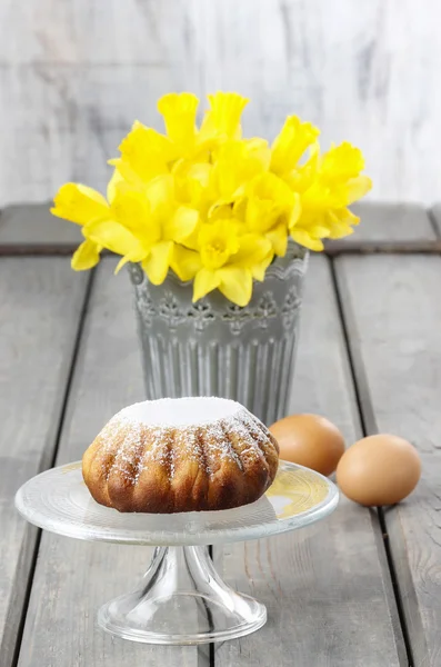 Daffodils in silver bucket on grey wooden table and easter yeast — Stock Photo, Image