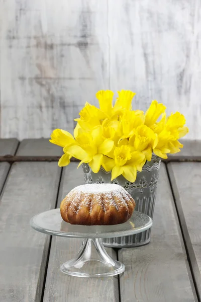 Daffodils in silver bucket on grey wooden table and easter yeast — Stock Photo, Image