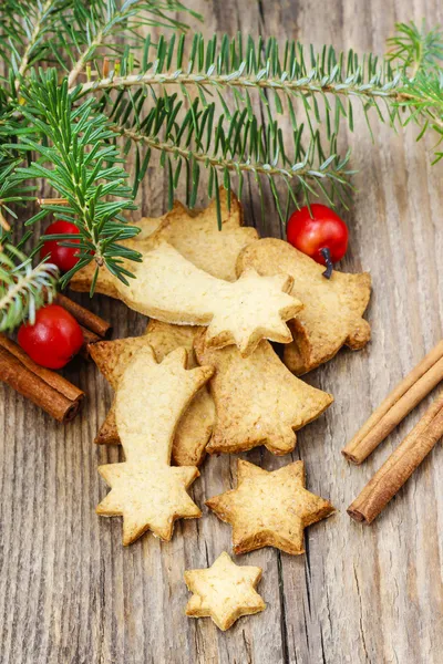 Galletas de Navidad sobre mesa de madera bajo rama de abeto . —  Fotos de Stock