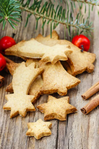 Galletas de Navidad sobre mesa de madera bajo rama de abeto . — Foto de Stock