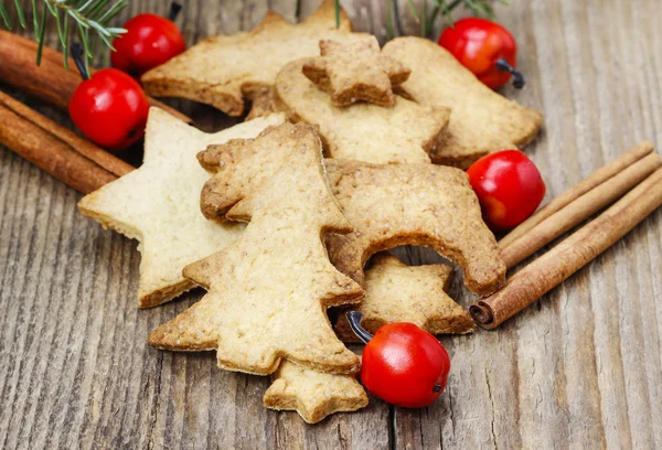 Galletas de Navidad sobre mesa de madera bajo rama de abeto . —  Fotos de Stock