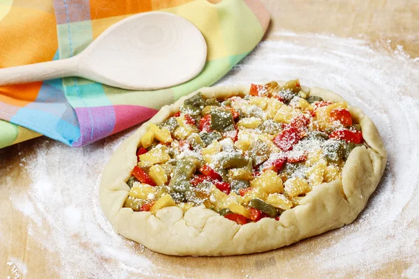 Vegetable galette on wooden kitchen board before baking. — Stock Photo, Image