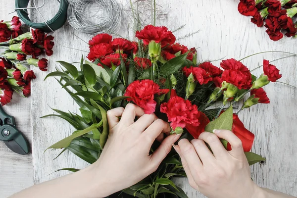 在工作的花店。女人做束红色的康乃馨 — 图库照片