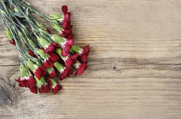 Μπουκέτο από κόκκινα λουλούδια Γαρύφαλλο σε ξύλινα φόντο. κάτοψη, — Φωτογραφία Αρχείου