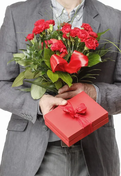 Мужчина держит букет красных гвоздик и красную подарочную коробку с большим — стоковое фото