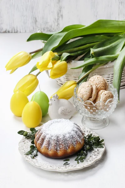 Wielkanocne ciasto i bukiet żółtych tulipanów na stole — Zdjęcie stockowe