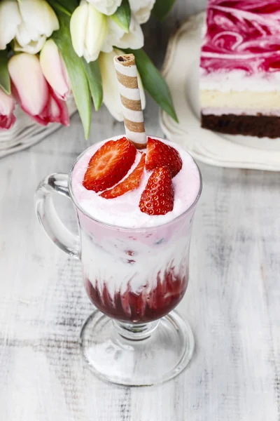 Strawberry milkshake and piece of cake in the background — Stock Photo, Image