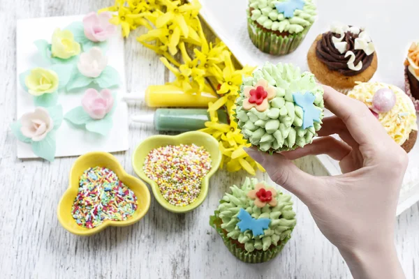 Woman decorates easter cupcakes — Stock Photo, Image