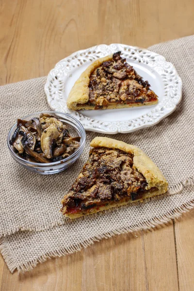 Bowl of raw mushrooms and mushroom galette in the background — Stock Photo, Image