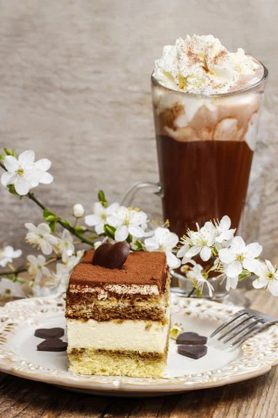 Tiramisu cake on white plate. Blossom apple branch and cup of ir — Stock Photo, Image