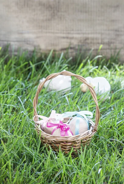 Корзина с пасхальными яйцами стоит на свежей траве — стоковое фото