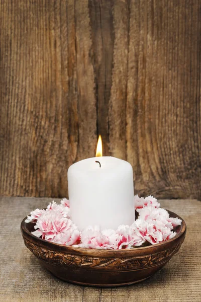 白色的蜡烛在老式木碗香石竹花间 — 图库照片