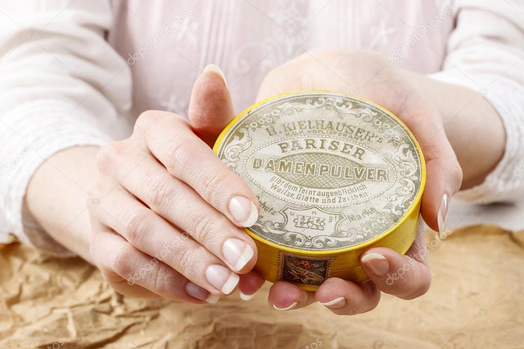 Woman holding vintage compact powder in beautiful hands