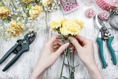 Florist at work. Woman making bouquet of yellow carnations clipart