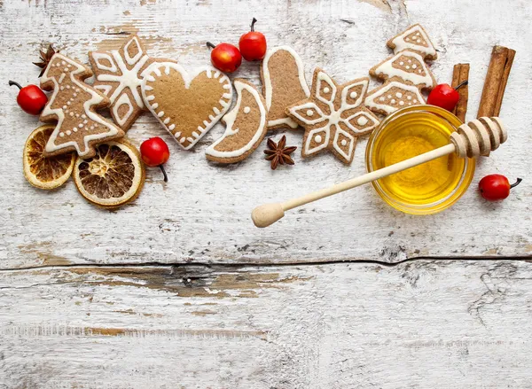 Galletas de Navidad de pan de jengibre y un tazón de miel en una mesa de madera . — Foto de Stock