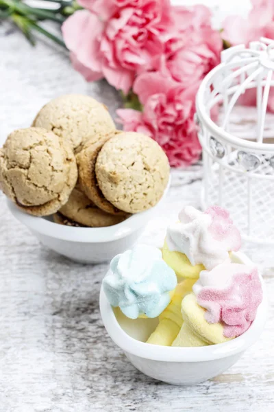 Kom marshmallows en kom van Parijse macarons op wit hout — Stockfoto