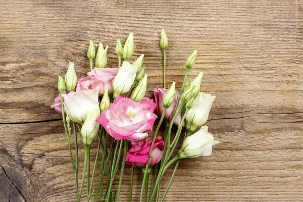Kytice růžových eustoma na dřevěný stůl — Stock fotografie