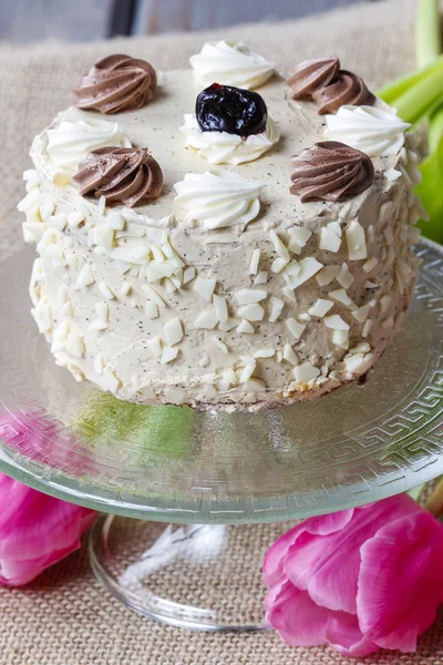 Vanilla wedding cake on cake stand, pink tulips in the backgroun — Stock Photo, Image