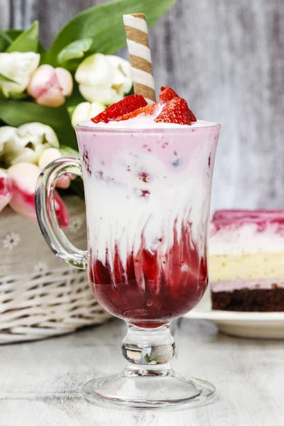 Strawberry milkshake and piece of cake in the background — Stock Photo, Image