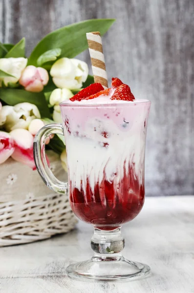 Erdbeer-Milchshake und ein Stück Kuchen im Hintergrund — Stockfoto