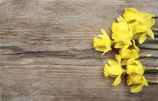 Hermosos narcisos amarillos sobre tabla de madera marrón. Vista superior, copia — Foto de Stock