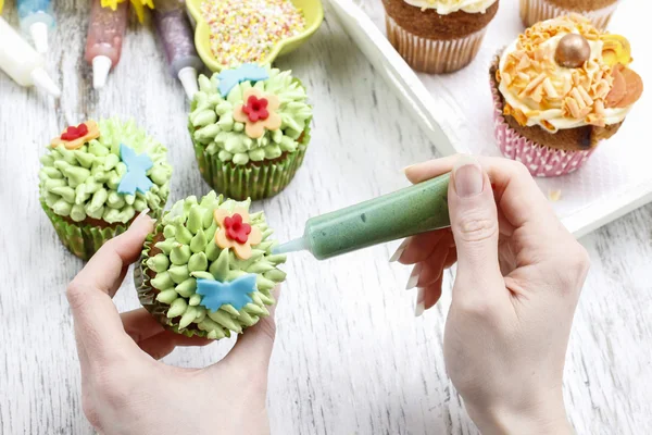 Woman decorates easter cupcakes — Stock Photo, Image